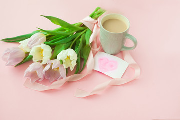 Fototapeta na wymiar Bouquet of tulips and a coffee cup on a pink pastel background. Wonderful spring breakfast on Mother's Day or Women. Flat lay. View top. Selective focus.