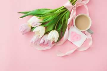 Bouquet of tulips and a coffee cup on a pink pastel background. Wonderful spring breakfast on Mother's Day or Women. Flat lay. View top. Selective focus.