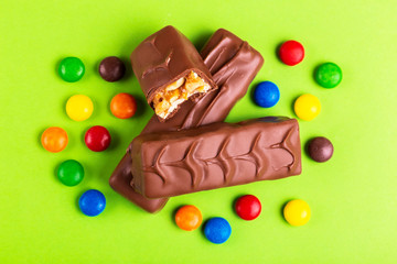 Tasty chocolate bars with toffee and colorful glazed round candies
