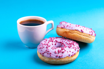 Two tasty lilac donuts with sprinkle, cup of strong coffee