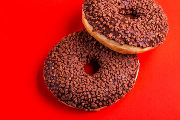 Two delicious chocolate donuts with sprinkle on bright red background