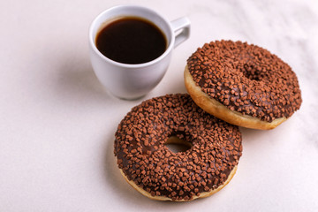 Two delicious chocolate donuts with sprinkle and cup of coffee