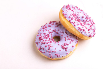 Two delicious lilac donuts with sprinkle on light marble background