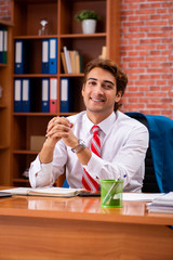 Young handsome employee sitting in the office  