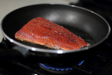 Wild caught Coho salmon frying in a pan with the skin side down.