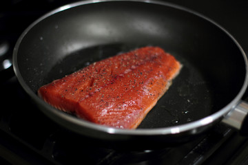 Wild caught Coho salmon frying in a pan with the skin side down.