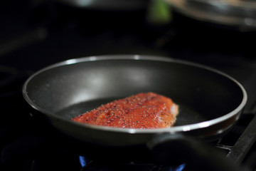Wild caught Coho salmon frying in a pan with the skin side down.