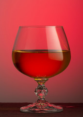 A glass of brandy on a red background