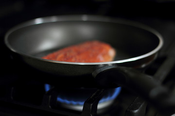 Wild caught Coho salmon frying in a pan with the skin side down.