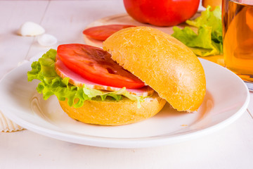 Delicious homemade sandwich with lettuce, ham and tomato close up on a light background