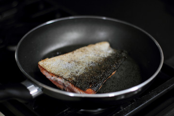 Fototapeta premium Wild caught Coho salmon frying in a pan with the skin side up.