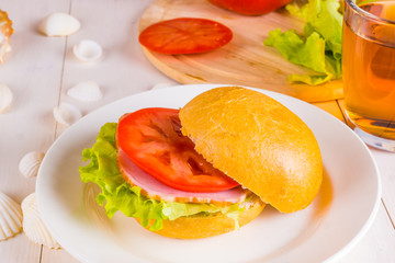 Delicious homemade sandwich with lettuce, ham and tomato close up on a light background