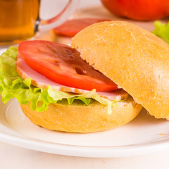 Delicious homemade sandwich with lettuce, ham and tomato close up on a light background