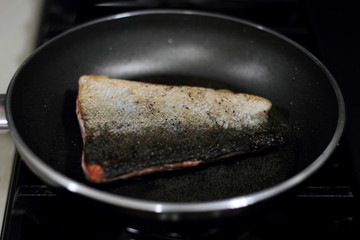 Wild caught Coho salmon frying in a pan with the skin side up.