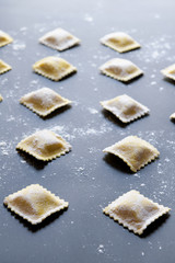 rows of raw homemade ravioli on a dark background