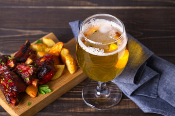 Glass of beer and grilled pork spare ribs with fry, tasty snack to beer. Beer and food concept. Ale...