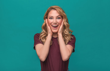 Portrait of blonde surprised emotional girl on blue background.