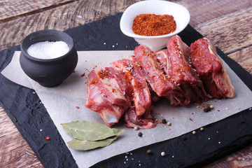 Raw fresh meat, uncooked lamb or beef ribs with pepper, garlic, salt and spices on dark stone background, Ready for cooking. copy space.