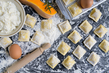 traditional raw ravioli with pumpkin on a wooden table with flour, handmade, cooking process