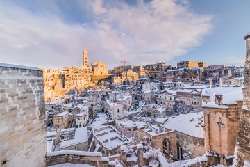 Fototapeta na wymiar panoramic view of typical stones Sassi di Matera and church of Matera 2019 under blue sky with clouds and snow on the house, concept of travel and christmas holiday,capital of europe culture 2019