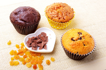 Assorted with Delicious homemade cupcakes with raisins and chocolate chips isolated on textile background. Muffins. Top view.