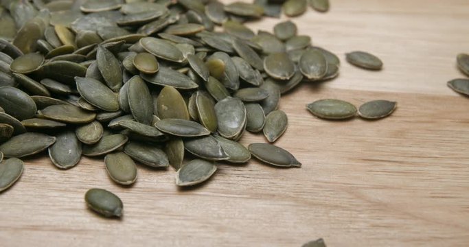 Pumpkin seeds falling and rotating studio macro