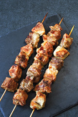Appetizing ruddy kebabs on a dark stone surface. Top view.
