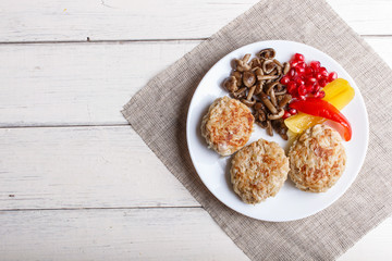 meatballs with rice mushrooms, sweet peppers and pomegranate seeds on white wooden background.