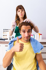 Woman hairdresser applying dye to man hair