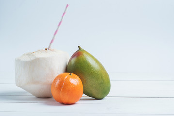 Drinks coconut with straw, mango and mandarin.