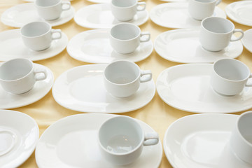 White ceramic cups of coffee that is still empty, arranged orderly on the table.