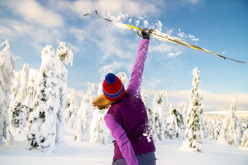Woman is holding skis up in a gesture of victory