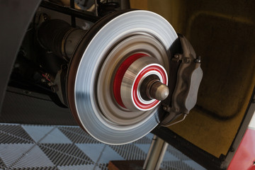 Workers are checking the rear brakes of a supercar in the garage