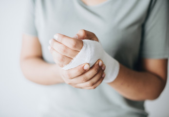 Woman with gauze bandage wrapped around her hand - obrazy, fototapety, plakaty