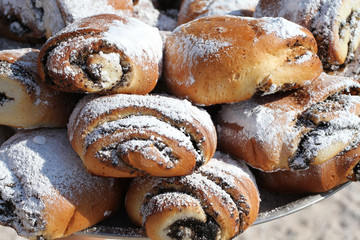 Buns with poppy seeds, sprinkled with powdered sugar, stacked on top of each other on the tray. Closeup