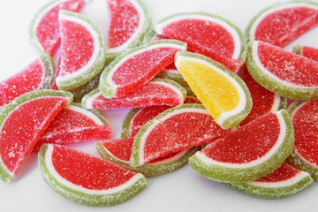 Sweet marmalade in the form of slices of watermelon and lime lies on the white surface of the store counter. Stand out from the crowd