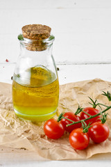 tomatoes with oil bottle on white wooden background