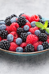 Fresh berry salad on blue dishes. Vintage wooden background.