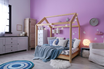 Child's room interior with comfortable bed and garland