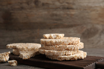 Wooden board with crunchy rice cakes on table