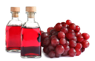 Bottles with wine vinegar and fresh grapes on white background