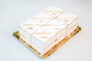 cream pastries in a gold tray on white background