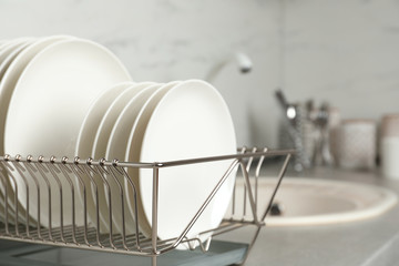 Drying rack with clean dishes on kitchen counter. Space for text