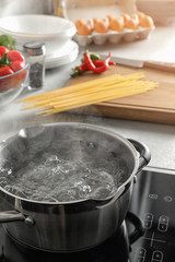 Pot with boiling water on electric stove in kitchen
