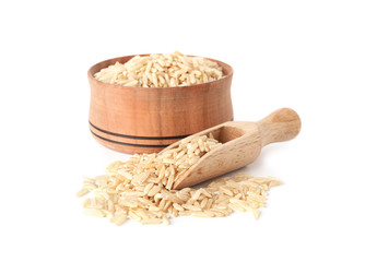 Bowl and scoop with uncooked brown rice on white background