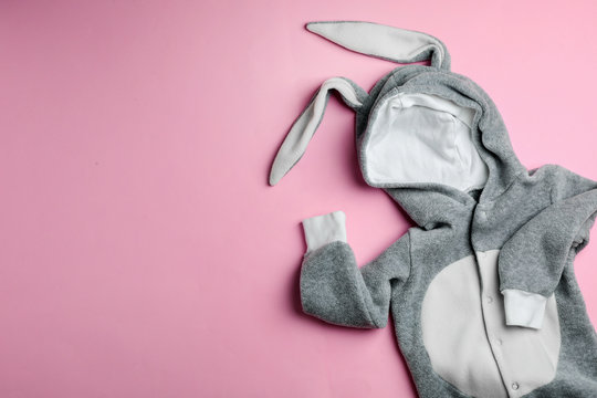 Adorable bodysuit with bunny ears and space for text on color background, flat lay. Baby accessories