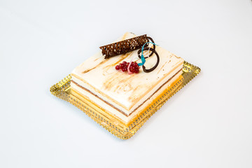 white chocolate cake on a gold tray on white background