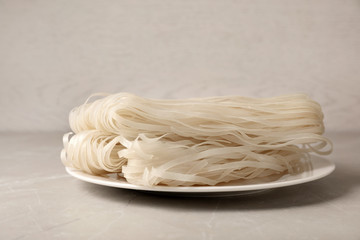 Plate with raw rice noodles on table. Delicious pasta