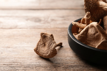 Composition of dried mushrooms and plate on wooden background