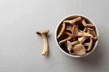 Bowl of dried mushrooms on color background, top view with space for text